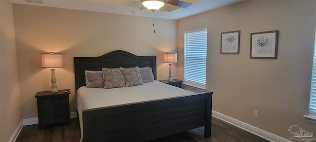 bedroom with dark wood-style floors, multiple windows, and baseboards