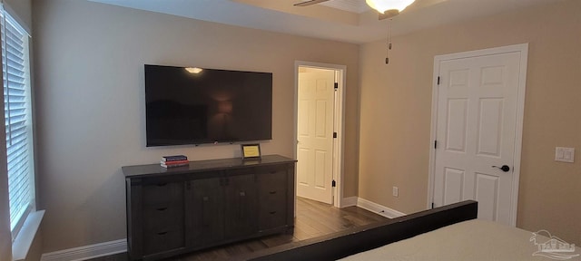 bedroom with dark wood-style flooring, a raised ceiling, and baseboards