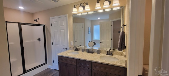 full bathroom with double vanity, a shower stall, and a sink