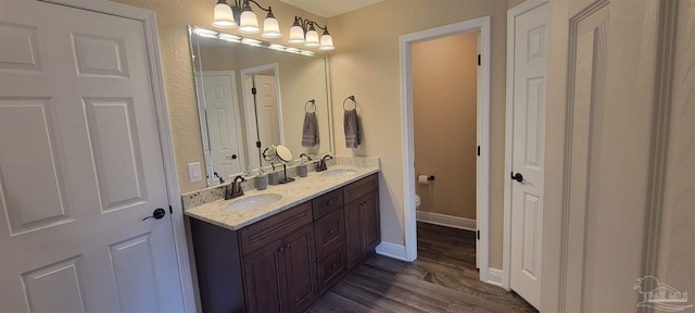 full bathroom featuring toilet, double vanity, a sink, and wood finished floors