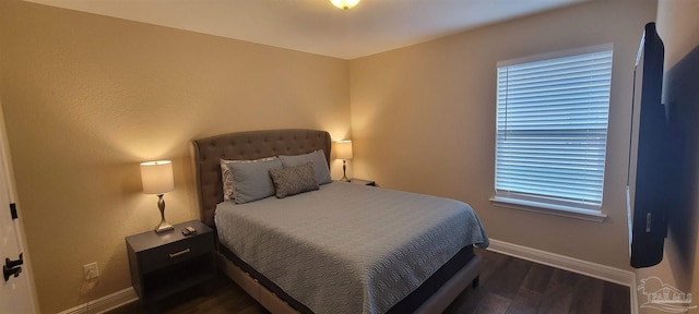 bedroom with dark wood-type flooring and baseboards