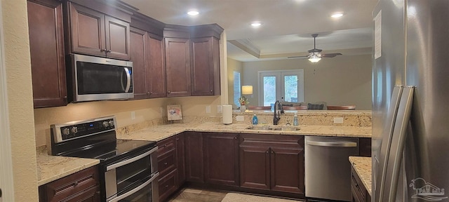 kitchen featuring a raised ceiling, appliances with stainless steel finishes, a sink, and light stone countertops