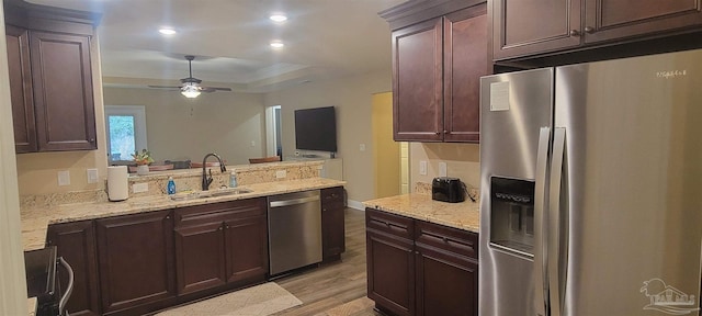 kitchen featuring stainless steel appliances, light wood-style flooring, a sink, ceiling fan, and light stone countertops