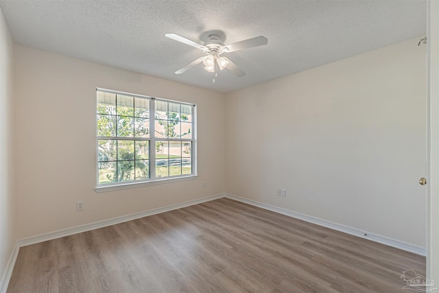 unfurnished room with a textured ceiling, baseboards, and wood finished floors