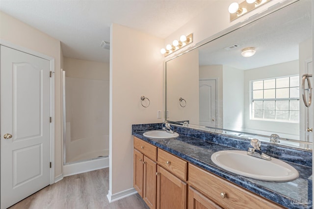 bathroom featuring double vanity, visible vents, wood finished floors, and a sink