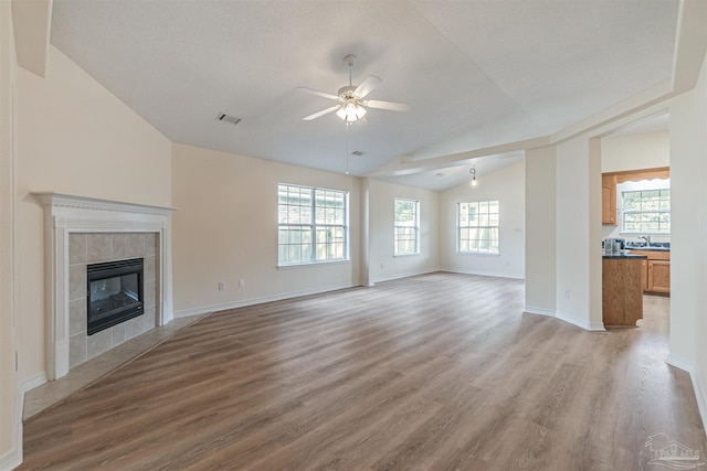 unfurnished living room featuring visible vents, a fireplace, light wood-type flooring, and lofted ceiling