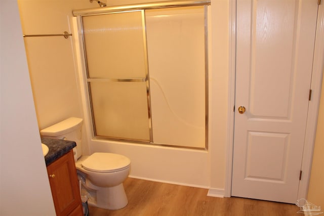 full bath with enclosed tub / shower combo, toilet, wood finished floors, and vanity