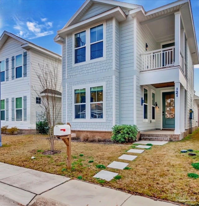 view of front of property with a balcony and a front lawn