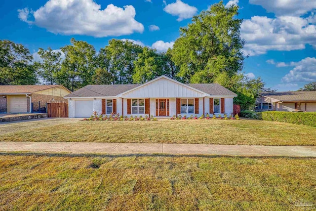 ranch-style home with a front lawn, covered porch, and a garage