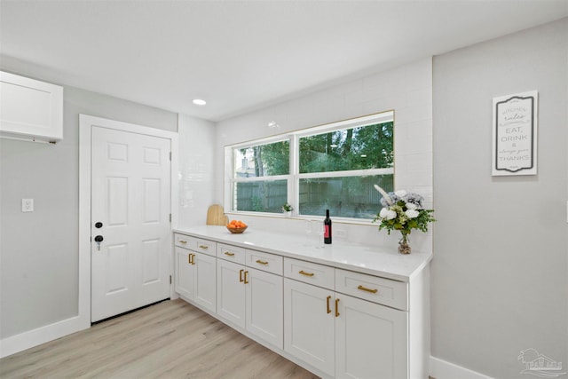 kitchen featuring white cabinets, light stone counters, and light wood-type flooring