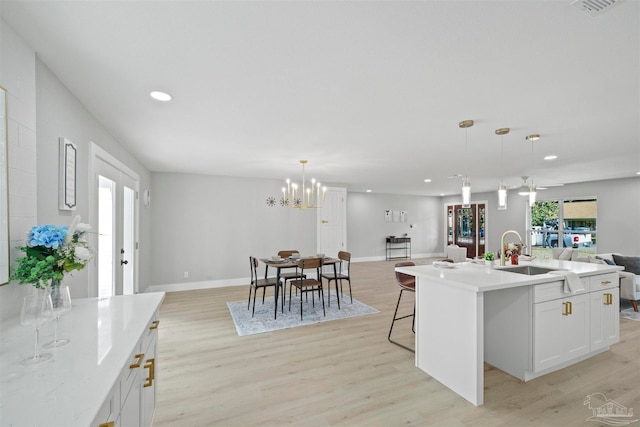 kitchen featuring sink, a kitchen island with sink, light hardwood / wood-style flooring, and decorative light fixtures