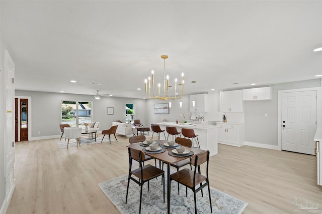 dining room with light hardwood / wood-style flooring, sink, and ceiling fan with notable chandelier