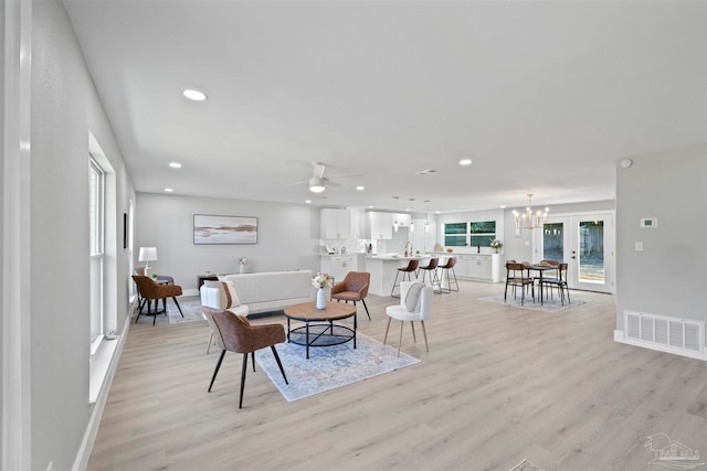 living room featuring light hardwood / wood-style floors and ceiling fan with notable chandelier