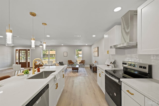 kitchen with hanging light fixtures, light hardwood / wood-style flooring, sink, wall chimney exhaust hood, and stainless steel appliances