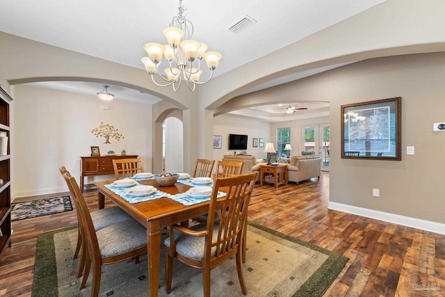 dining space with ceiling fan with notable chandelier and dark hardwood / wood-style floors