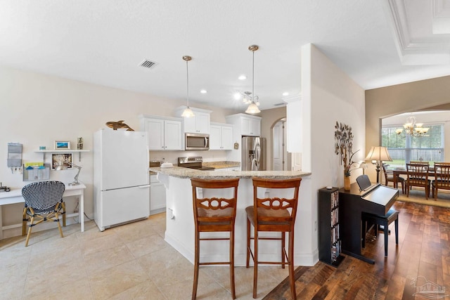 4951 Red Oak Dr, Milton, FL 32583 - kitchen featuring visible vents, white cabinetry, a kitchen bar, and stainless steel appliances