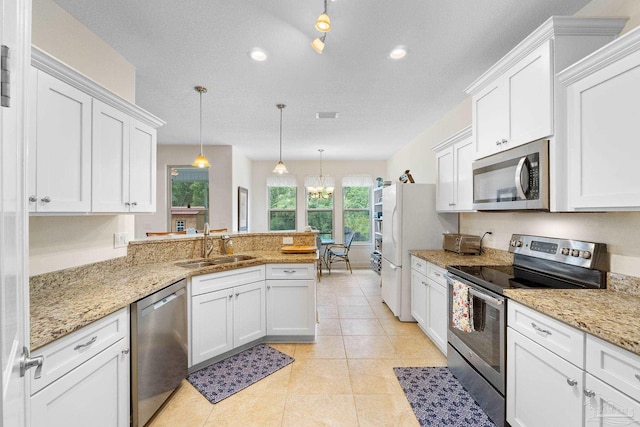 4951 Red Oak Dr, Milton, FL 32583 - kitchen with a peninsula, white cabinets, a sink, appliances with stainless steel finishes, and a notable chandelier