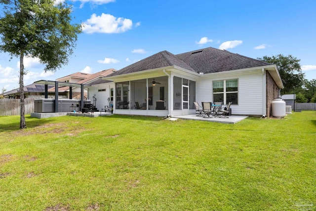 rear view of house featuring ceiling fan, a sunroom, a lawn, and a patio