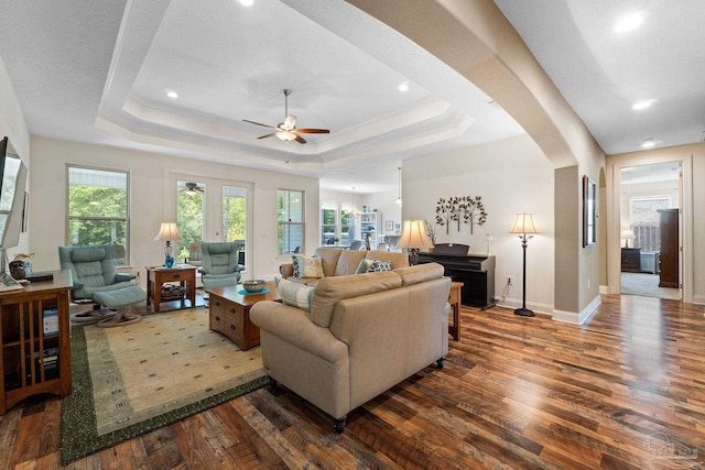 living room with a wealth of natural light, a raised ceiling, ceiling fan, and dark hardwood / wood-style floors