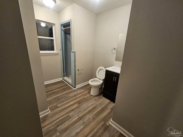 bathroom featuring hardwood / wood-style flooring, vanity, a shower with door, and toilet