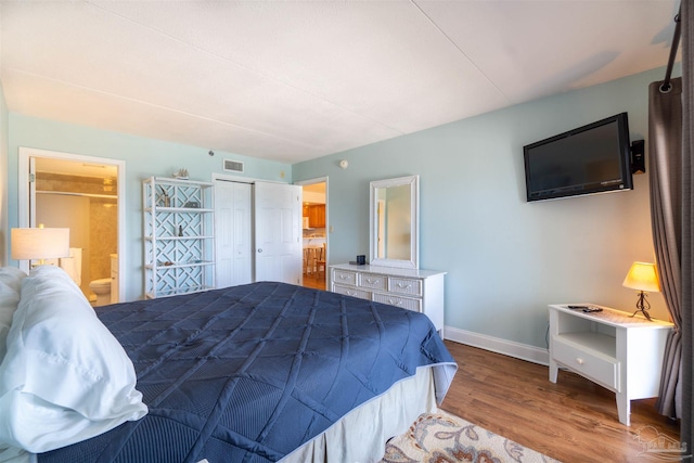 bedroom featuring connected bathroom, hardwood / wood-style floors, and a closet