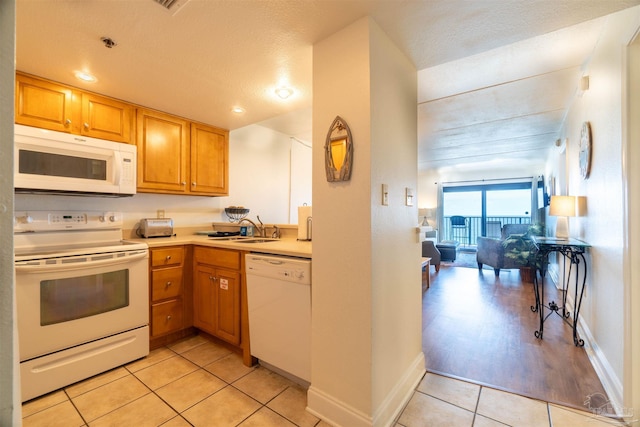 kitchen featuring sink, light tile patterned floors, a textured ceiling, and white appliances