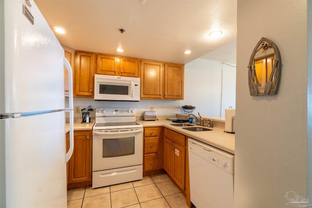 kitchen with light tile patterned flooring, white appliances, sink, and a textured ceiling