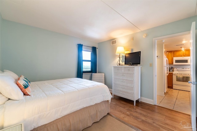 bedroom featuring light hardwood / wood-style flooring and white refrigerator