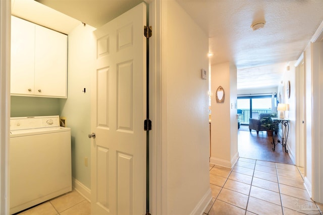 clothes washing area featuring cabinets, washer / dryer, light tile patterned floors, and a textured ceiling