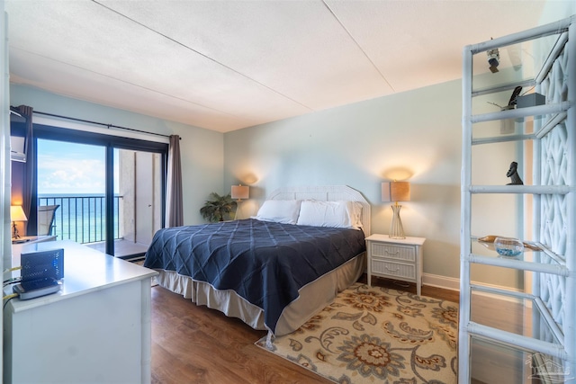 bedroom featuring a water view, dark wood-type flooring, and access to outside