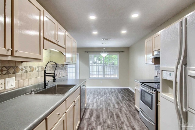 kitchen featuring decorative backsplash, hardwood / wood-style floors, stainless steel appliances, sink, and decorative light fixtures