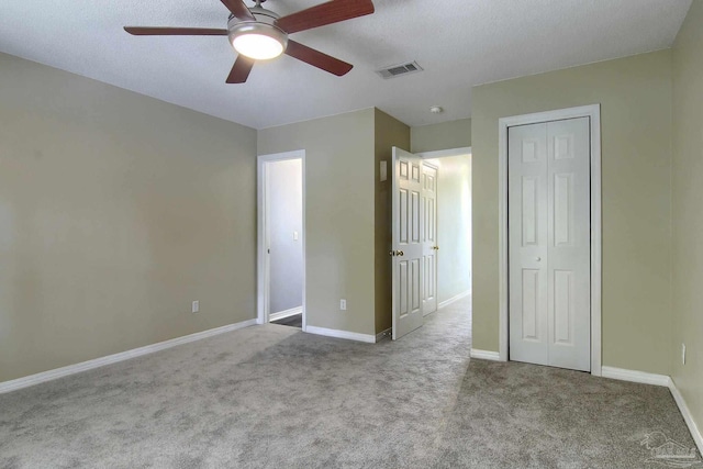 unfurnished bedroom with light carpet, a textured ceiling, and ceiling fan