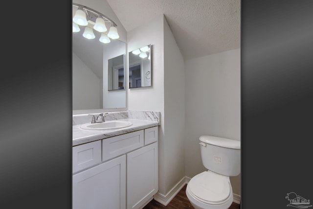 bathroom with lofted ceiling, hardwood / wood-style flooring, toilet, vanity, and a textured ceiling