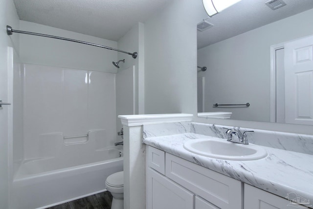 full bathroom with hardwood / wood-style floors, a textured ceiling, toilet, vanity, and tub / shower combination