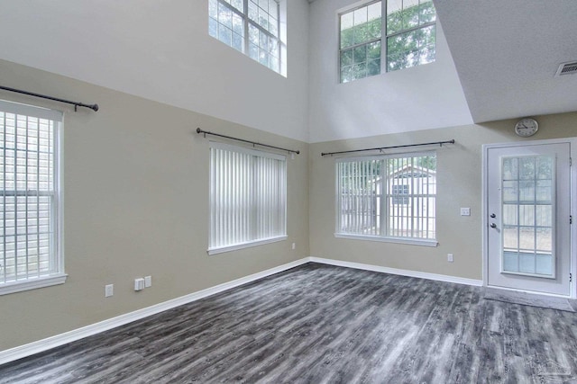 spare room featuring dark wood-type flooring, a textured ceiling, and a towering ceiling