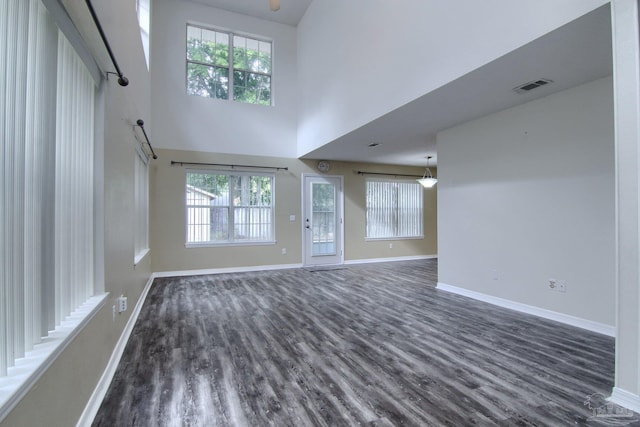 unfurnished living room with a wealth of natural light, a high ceiling, and dark hardwood / wood-style floors