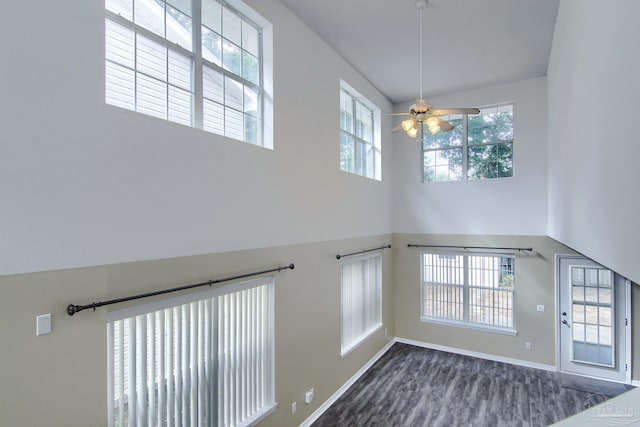 foyer featuring a wealth of natural light, ceiling fan, a towering ceiling, and dark hardwood / wood-style flooring