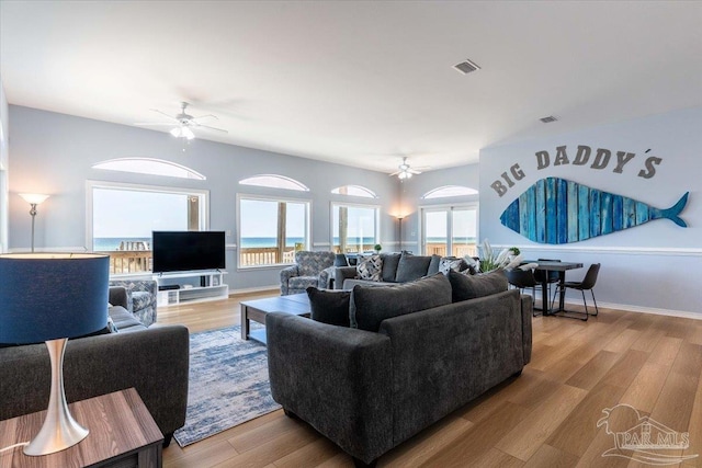 living room with visible vents, plenty of natural light, a ceiling fan, and wood finished floors