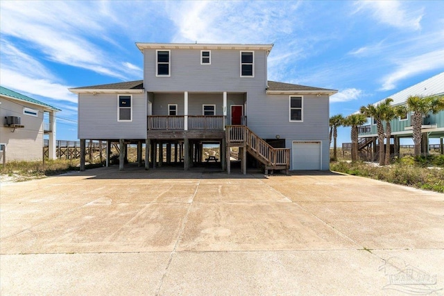 rear view of property with driveway, a porch, stairway, a garage, and a carport