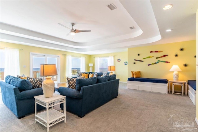 living room with carpet, visible vents, a tray ceiling, recessed lighting, and ceiling fan