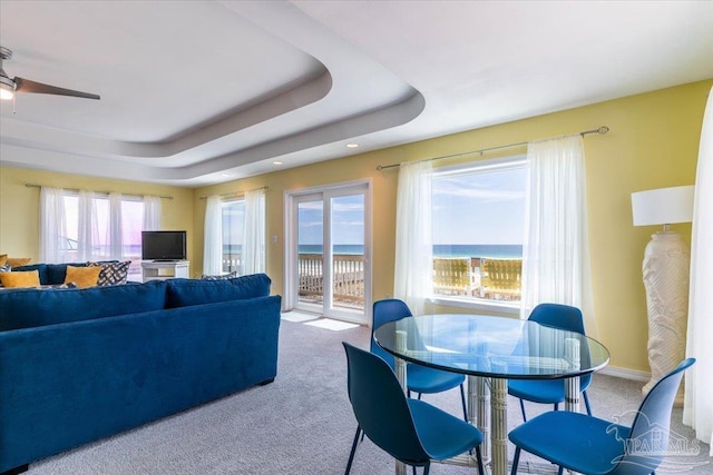 living room featuring baseboards, carpet, a tray ceiling, and a ceiling fan