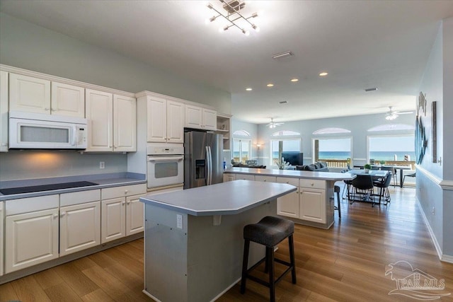 kitchen with a kitchen island, white appliances, a ceiling fan, and a peninsula