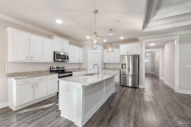 kitchen featuring decorative light fixtures, a kitchen island with sink, stainless steel appliances, white cabinetry, and a sink