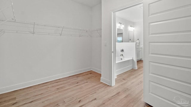 walk in closet with light wood-style floors