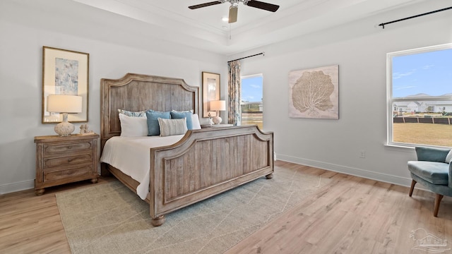 bedroom with light wood finished floors, baseboards, and multiple windows