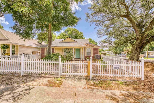 1000 N D St, Pensacola, FL 32501 - view of front of house featuring brick siding, covered porch, roof with shingles, and a fenced front yard
