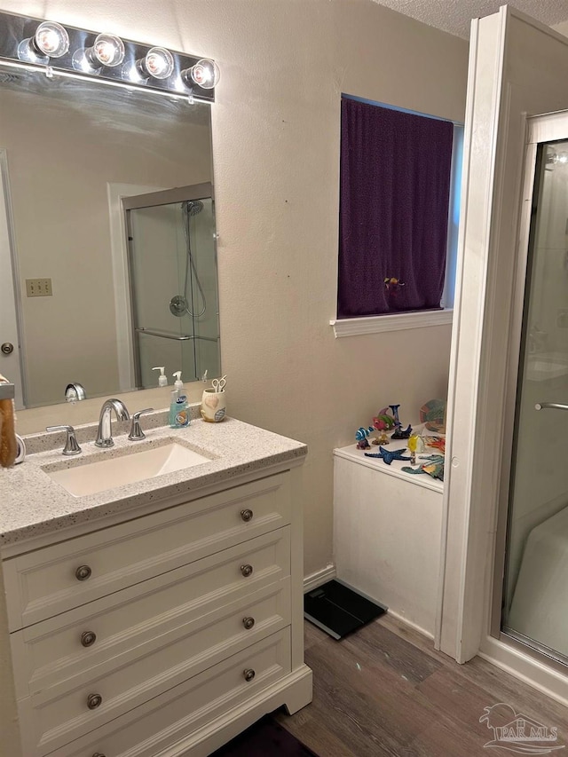 bathroom with a stall shower, wood finished floors, and vanity