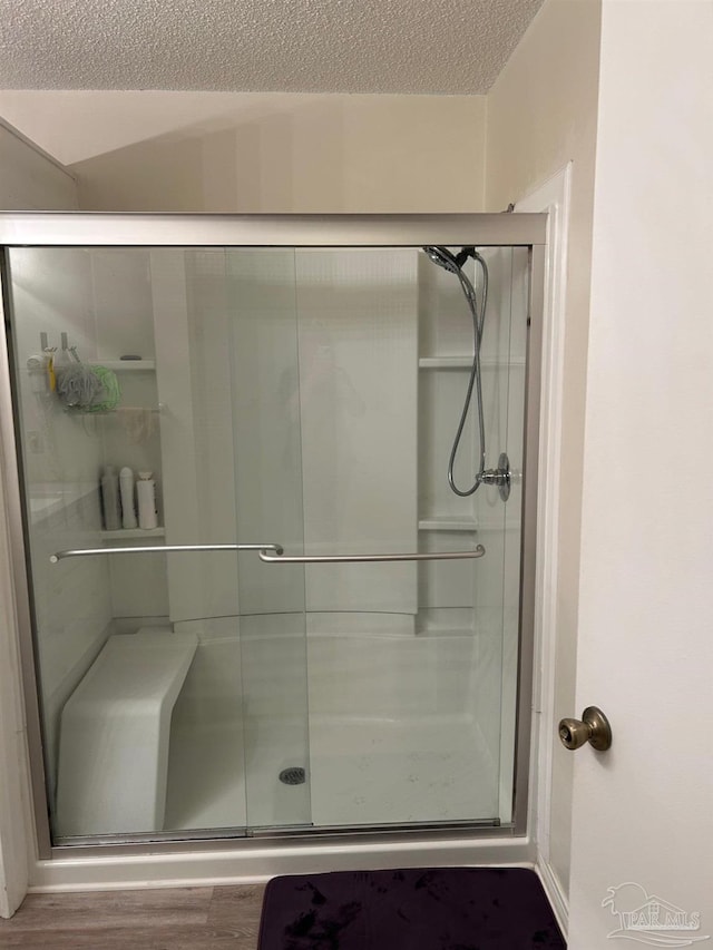 bathroom with a stall shower, wood finished floors, and a textured ceiling