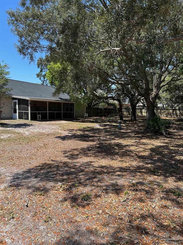 view of yard featuring fence and a sunroom
