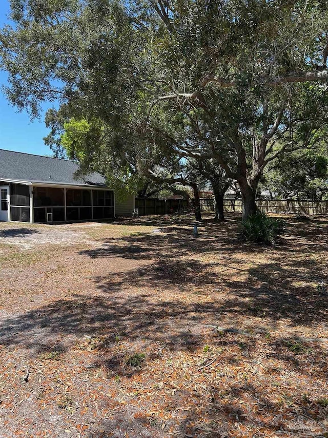 view of yard with fence and a sunroom